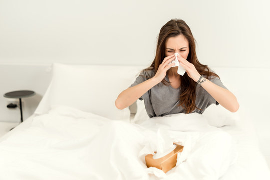 Beautiful young woman waking sick and ill in the morning sneezing. health care concept