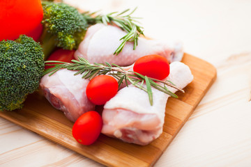 Raw chicken legs with spices, vegetables and rosemary on the dark wooden cutting board. Recipes, healthy food, lifestyle concept. Top view. Close up.