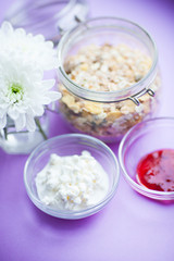 Healthy food concept. Muesli, fruits, curd and jam for productive day on the purple background. Top view. Space for a text.