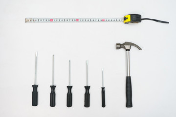 Top view of composed hammer with screwdrivers and tape measure on white background