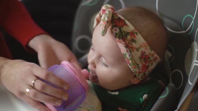 the little girl is drinking from the trough