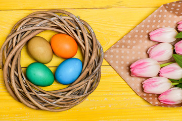 Spring vibes. Easter is coming. Colorful bright eggs and bouquet fresh tulip flowers on yellow background top view. Spring holiday. Tradition celebrate easter. Happy easter season. Easter eggs symbol