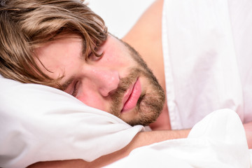 Stretch after wake up in the morning. Man eyes are closed with relaxation. Man with eyes still closed reaching button on the clock to turn it off.