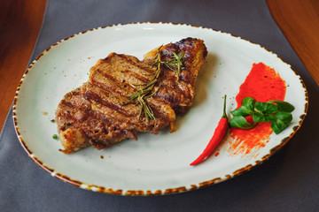 Ribeye steak with red pepper and rosemary on plate, selective focus
