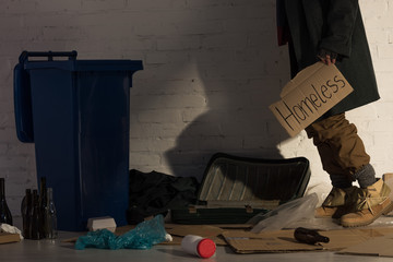 partial view of homeless man holding piece of cardboard with 