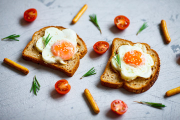 Fried eggs sandwiches with fresh tomatoes and rosemary on the tray background. Healthy breakfast or snacks. Lifestyle, diet, food styling concept. Top view. Close up. Space for a text.