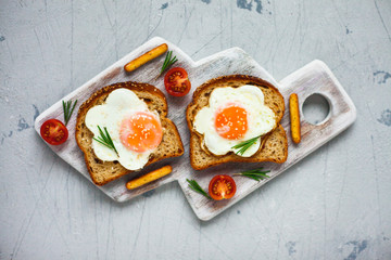 Fried eggs sandwiches with fresh tomatoes and rosemary on the tray background. Healthy breakfast or snacks. Lifestyle, diet, food styling concept. Top view. Close up. Space for a text.