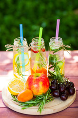 Fresh detox juices in glass bottles on the wooden background. Fruits and berries. Lifestyle, vegan food and drink, health care, diet and summer concept. Top view. Close up.
