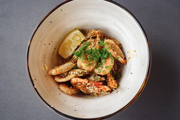 fried roasted shrimps in plate with lemon greens parsley garlic, top view