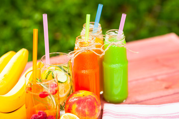 Fresh detox juices in glass bottles on the wooden background. Fruits and berries. Lifestyle, vegan food and drink, health care, diet and summer concept. Top view. Close up.
