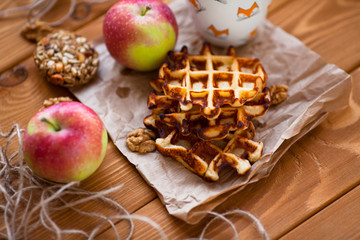 Fresh homemade waffles with apples and nuts for breakfast on the wooden background. Top view. Close up.