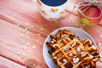 Fresh homemade waffles with apples and nuts for breakfast on the wooden background. Top view. Close up.