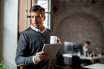 Businessman using digital tablet on coffee break and thinking of something.