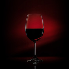 Red wine in a glass on a gradient black to red background. Studio shot.