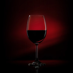 Red wine in a glass on a gradient black to red background. Studio shot.