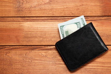 Black leather wallet with money on wooden background. Top view