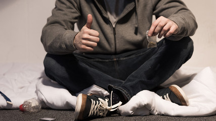 selective focus of addictive man holding pack of marijuana and showing thumb up
