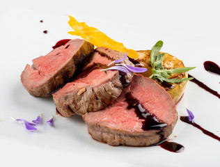 Veal medallions with wine sauce on white background