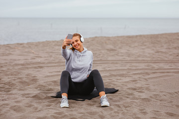 Young sports woman listens to music on the beach