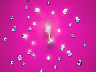 Metal butt plug and artificial diamonds are on a colored background.