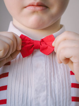 close-up neat little boy correcting his red bow tie. body parts hands and face child puts on scarlet bowtie. concept good breeding and education - Image