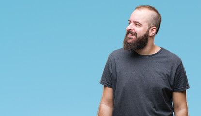 Fototapeta premium Young caucasian hipster man over isolated background looking away to side with smile on face, natural expression. Laughing confident.