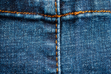 Fragment of a classic blue denim texture with orange stitching