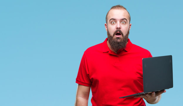 Young caucasian man using computer laptop over isolated background scared in shock with a surprise face, afraid and excited with fear expression