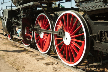 large steel wheels of old steam locomotive red with white outline