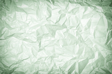 Texture of crumpled greenish paper, background. Photo with vignette.