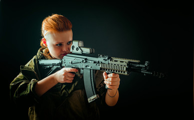 Portrait of young woman with red hair, young girl takes aim at the sight in military uniform, Horizontal photo
