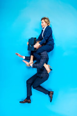 Man holding on shoulders shocked woman with briefcase on blue background