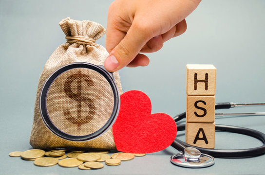 Wooden blocks with the word HSA and money bag with stethoscope. Health savings account. Health care. Health insurance. Investments. Tax-free medical expenses. Coins and dollar sign. Red heart
