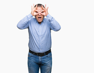 Fototapeta premium Middle age arab business man over isolated background doing ok gesture like binoculars sticking tongue out, eyes looking through fingers. Crazy expression.