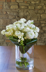 white bouquet in a glass jar on a wooden table