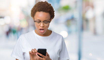 Young african american woman using smartphone over isolated background scared in shock with a surprise face, afraid and excited with fear expression