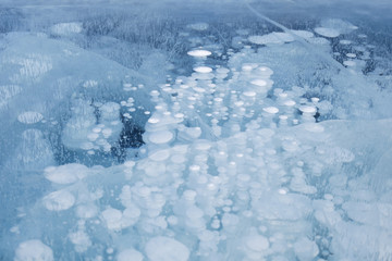 Fototapeta na wymiar Bubbles of methane gas frozen in clear ice