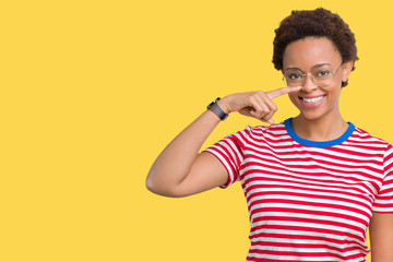 Beautiful young african american woman wearing glasses over isolated background Pointing with hand finger to face and nose, smiling cheerful