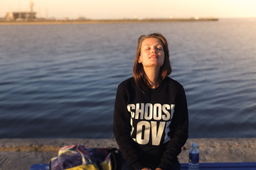 Relaxed beautiful young white caucasian woman with her eyes closed facing to the sky. Wearing...
