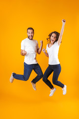 Fototapeta Full length photo of rejoicing couple screaming in surprise while jumping, isolated over yellow background obraz