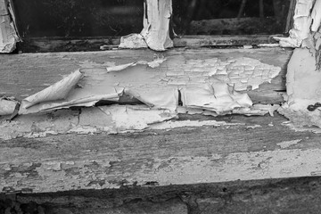 A close up of a weathered window sill with paint peeling away