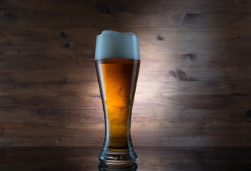 Glass of golden beer on wooden background
