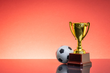 Trophy and ball in front of the red background. Selective focus