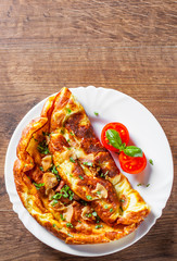 omelette with bacon in a white plate on wooden table