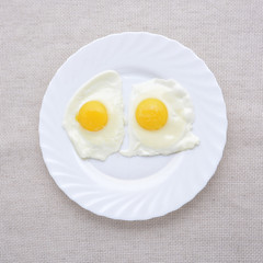 Two fried eggs on a white plate. Breakfast. Top view.