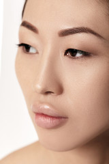 Obraz premium close-up portrait of beautiful young asian woman on white background closeup. girl with clean skin. Female lips after augmentation procedure