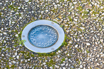 Recessed lighting in a gravel floor of a pedestrian walkway with water condensation against the glass