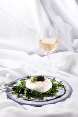 Burratta cheese with arugula and balsamic vinegar pearls on a white background