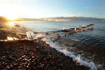 The old pier  The old dilapidated pier near the shore of lake Baikal is frozen with cold water and frost, it is illuminated by the sunrise at the beginning of winter near the village of Listvyanka