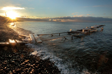 The old pier  The old dilapidated pier near the shore of lake Baikal is frozen with cold water and frost, it is illuminated by the sunrise at the beginning of winter near the village of Listvyanka